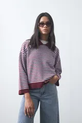 Sweater de punto a rayas horizontales en color bordó y celeste, con cuello polo y mangas largas con puños amplios. Presenta un diseño de calce relajado.
