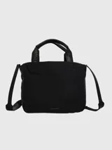 Cartera tipo tote de Hush Puppies, confeccionada en poliéster reciclado. Presenta un diseño minimalista en color negro con correas de mano y correa cruzada ajustable, ambas con el logo de la marca estampado. Incluye cierre de cordón en el compartimento principal y logo metálico discreto en la parte inferior.