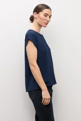 Blusa blanca con textura plumeti, de manga corta y cuello redondo.