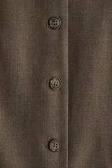 Chaleco largo de vestir color marrón oscuro, con cuello en V, cierre frontal de botones y bolsillos ribeteados. Presenta un corte entallado y abertura en la parte trasera.