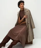 Vestido midi de Marfinno, confeccionado en una mezcla de viscosa y poliéster. Presenta un diseño sin mangas con cuello cerrado, corte recto en el busto y una cintura con recorte asimétrico que genera una falda con caída evasé.