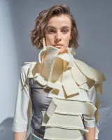 Bufandón de lana merino afieltrada color natural, formado por piezas horizontales unidas que generan una textura continua.