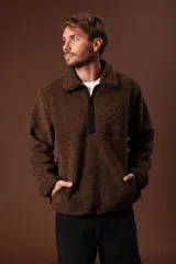 Cazadora de borreguillo color marrón, con cuello alto y cierre frontal parcial con cremallera. Presenta bolsillos laterales y diseño de manga larga.