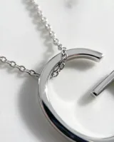 Collar de cadena fina con dije de letra inicial mayúscula de gran tamaño, disponible en acero plateado o con baño de oro.