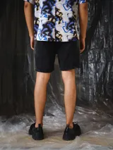 Short de denim negro con lavado degradé hacia los laterales, silueta recta y relajada de largo medio, con recortes verticales, bolsillos y pasacintos.