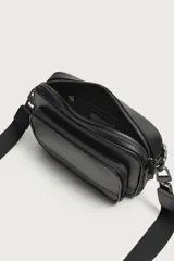 Bandolera de diseño rectangular con acabado texturizado y detalle liso en la parte inferior. Cuenta con un compartimento principal con cierre de cremallera, un bolsillo frontal con cierre y un bolsillo interior con cierre. Incluye asa de hombro ajustable y extraíble.