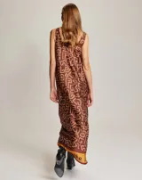 Vestido largo sin mangas con escote redondo, confeccionado en viscosa con un estampado geométrico tipo ikat en tonos marrones, naranjas y blancos, con detalle de texto en el ruedo.
