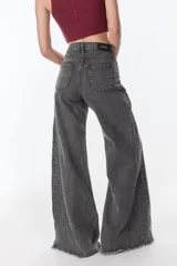 Pantalón de jean color gris oscuro con diseño de pierna ancha, tiro alto y ruedo desflecado. Presenta costuras verticales que recorren el largo de la pierna y bolsillos traseros clásicos.