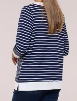 Buzo liviano de estilo deportivo-marinero y silueta semi holgada, confeccionado en tejido acanalado con diseño a rayas horizontales y verticales en azul marino y blanco. Cuenta con escote redondo amplio, cordón ajustable, bolsillo frontal tipo canguro, mangas tres cuartos con puños anchos y aberturas laterales en el ruedo.