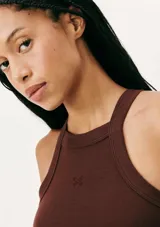 Musculosa de tejido acanalado en color naranja, con cuello redondo alto y detalle de pequeño bordado central en el pecho.