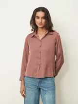 Camisa de manga larga con cuello clásico y cierre frontal de botones, confeccionada en tela con acabado satinado.