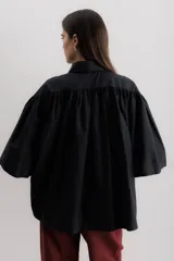 Camisa marrón con cuello clásico, abotonada al frente y mangas 3/4 abullonadas.