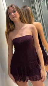 Vestido corto de encaje color bordó, strapless y ajustado al cuerpo, con detalle de volados en el borde inferior.