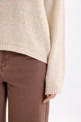 Sweater de punto de cinta en color crudo, de manga larga, con cuello redondo y diseño holgado.