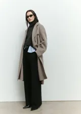 Abrigo largo de diseño oversize confeccionado en tejido con mezcla de lana. Presenta cuello con solapas de muesca, cierre frontal de doble botonadura y hombros caídos. Cuenta con dos bolsillos laterales y abertura posterior en el bajo.