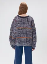 Sweater de punto con diseño geométrico y gráfico frontal en color rojo. Presenta cuello redondo, mangas largas holgadas y un ajuste suelto.