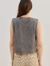 Musculosa crop de algodón con efecto acid wash en color lila, cuello redondo, hombreras marcadas y pequeño bordado central en el pecho.