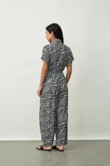 Mono largo negro de corte palazzo con camisa de mangas cortas con botones y lazo en la cintura.