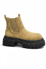 Bota tipo chelsea de gamuza color beige, con paneles elásticos laterales y suela track de goma negra con textura rugosa.