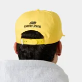 Gorra amarilla con visera curva, confeccionada en algodón. Cuenta con bordado frontal con el texto "EMEST ALWAYS" y un escudo distintivo en negro.