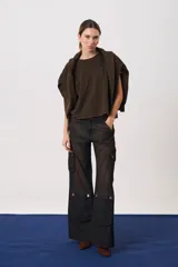 Pantalón cargo de tiro medio con pierna amplia y corte recto. Presenta bolsillos laterales tipo cargo con solapas y botones, además de recortes estructurales en la parte inferior de las piernas. Confeccionado en denim de algodón.