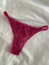 Bombacha tipo colaless confeccionada en encaje fucsia con detalles de terminaciones festoneadas y tiras laterales regulables.