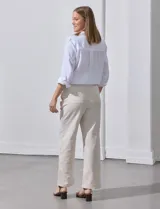 Pantalón de lino de corte recto y tiro medio, con pretina elástica ancha y lazo de ajuste frontal. Presenta bolsillos laterales verticales y bolsillos traseros.