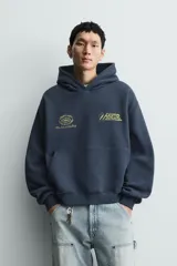 Sudadera tipo hoodie de corte relajado en color azul oscuro con efecto lavado. Presenta capucha, manga larga, bolsillo frontal tipo canguro y detalles estampados en color dorado en el pecho.