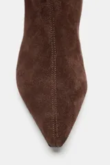 Bota de caña alta confeccionada en serraje, con diseño estilo cowboy, acabado en punta y tacón kitten en bloque.