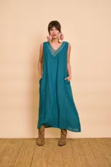 Vestido largo color verde petróleo con escote en V, detalles de bordado metálico en el escote y bolsillos laterales.