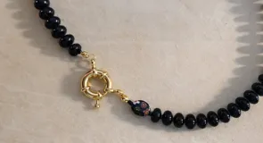 Collar compuesto por varias hileras de piedras naturales de calcedonia pulida en tonos verde, negro y bordó, con detalle de cuenta de cristal de Murano y cierre marinero con baño dorado.