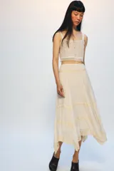 Falda midi de tiro medio en color crudo, con tejido de viscosa y bajo asimétrico decorado con encaje. Cuenta con cierre lateral con cremallera oculta en costura.