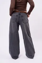 Jean wide-leg de tiro bajo, color gris carbón deslavado, con diseño amplio y fluido, bolsillos laterales y traseros clásicos.