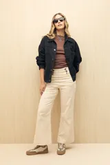 Pantalón de tiro alto color crudo, de corte ancho y con botones decorativos en la cintura.