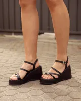Sandalias de cuero negro con plataforma y taco chino, tiras finas en el empeine y tira ajustable con hebilla en el tobillo.