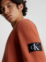 Remera de manga larga con cuello redondo y puños de canalé, confeccionada en punto gofrado de algodón. Presenta una insignia con el logo de Calvin Klein en la manga.