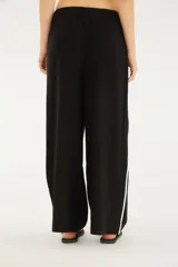 Pantalón negro de silueta amplia y caída relajada, con cintura elástica ajustable mediante cordón blanco y detalles de vivos laterales en color blanco.