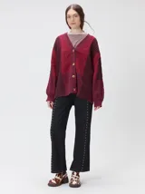 Cardigan oversize de tejido de punto grueso con diseño de bloques de color en tonos beige y marrón. Presenta cuello en V, cierre frontal con botones, mangas largas abullonadas y parches decorativos en el pecho y el hombro.