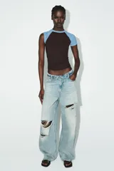 Camiseta de manga corta estilo raglán, con cuerpo principal marrón oscuro y mangas cortas en color celeste claro. Presenta cuello redondo con costuras a contraste.