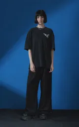 Remera de manga corta con cuello redondo y calce oversize, confeccionada en algodón premium con efecto de lavado nevado. Presenta una estampa gráfica en la espalda con diseño de palomas y texto alusivo.