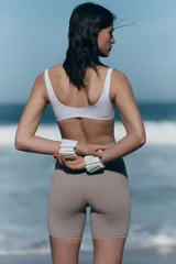 Top deportivo blanco para yoga, con escote en V, breteles anchos y detalle girado en el frente. Incluye copas forradas con relleno extraíble.