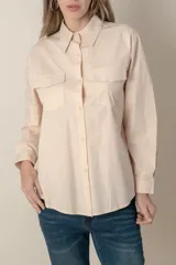 Camisa color crema de manga larga con dos bolsillos frontales con solapa.