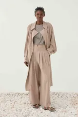 Trench largo beige de corte recto, con cuello de solapas clásicas, mangas largas con puño abotonado y tejido liviano de lyocell.