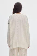 Buzo negro de tejido de ochos, con cuello redondo y diseño oversized de corte largo y amplio con tajos laterales.