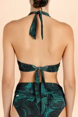 Top de bikini estilo halter con diseño de ondas en tonos negro y turquesa. Presenta un detalle de avío metálico con piedra central en el escote y tiras para anudar al cuello.
