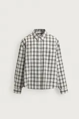 Camisa relaxed fit confeccionada en tejido de mezcla de algodón con textura irregular, diseño a cuadros en tonos gris, marrón y blanco, con cuello solapa, manga larga con puño abotonado, bolsillo de parche en el pecho y cierre frontal con botones.