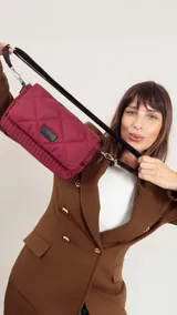 Bandolera capitoneada color bordó, con bolsillo interno, correa de galón ajustable y tapa con broche.