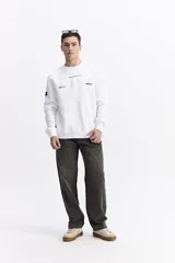 Buzo de algodón color celeste, con cuello redondo, puños y bolsillos laterales. Presenta estampados con texto en el pecho y un parche en la manga.