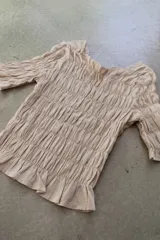 Remera de algodón con textura fruncida en todo el cuerpo, mangas tres cuartos y terminación con volado en el ruedo.