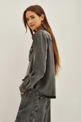 Camisa de estilo tejano en color negro lavado, con cuello camisero, cierre frontal con botones metálicos y dos bolsillos delanteros con solapa.